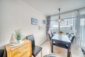 A dining area with a wooden table, black chairs, a small potted plant, and a ceiling light fixture. - Vrbo Property (Heiligenhafen)