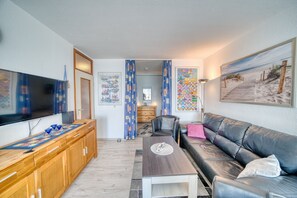 A modern living room with a flat-screen TV, wooden cabinet, leather sofa, and a coffee table. - Vrbo Property (Heiligenhafen)