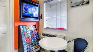 A small room with a television mounted on the wall, a table, and a chair.