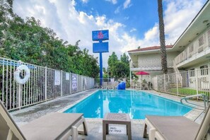 A swimming pool with lounge chairs, a lifebuoy, and a 'NO LIVING' sign.