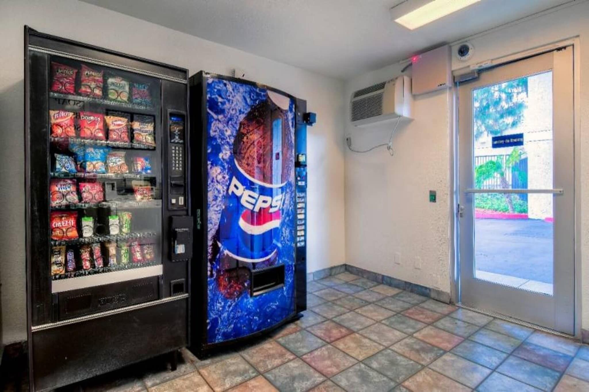 A vending machine with a Pepsi logo and a snack vending machine with various snacks.