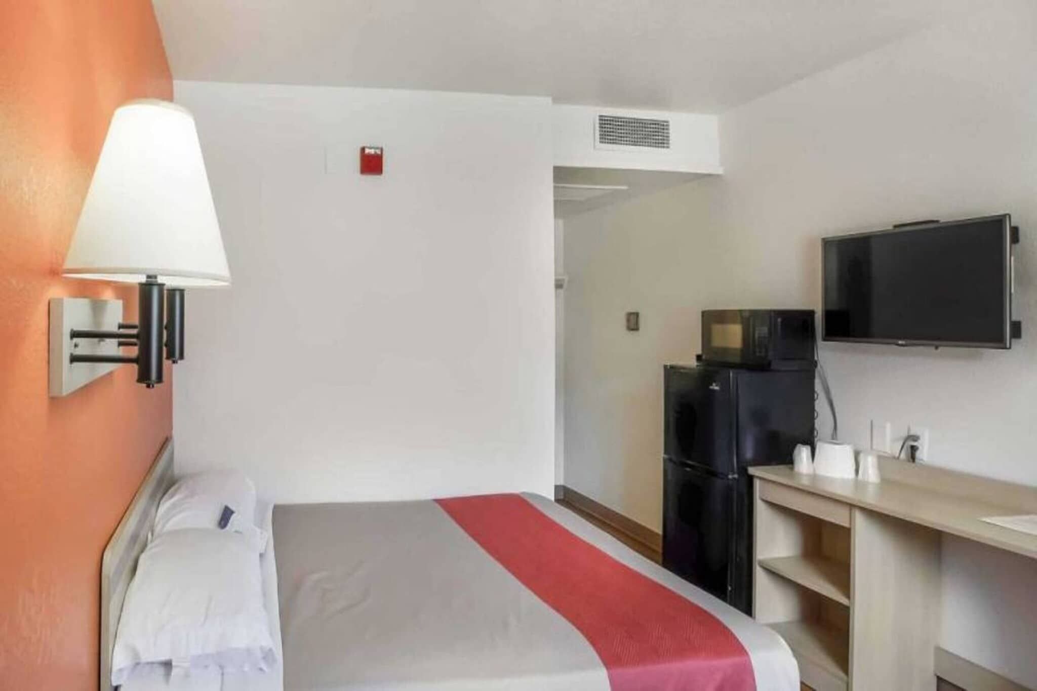 Une chambre d’hôtel équipée d’un lit, d’un bureau, d’une télévision et d’un four à micro-ondes.