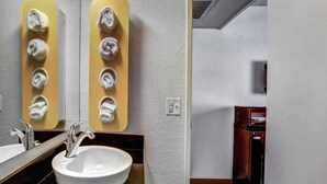 A bathroom with a sink, mirror, towel rack, and a wall-mounted heater. - 1 Queen Bed | Smoking (Medford OR)