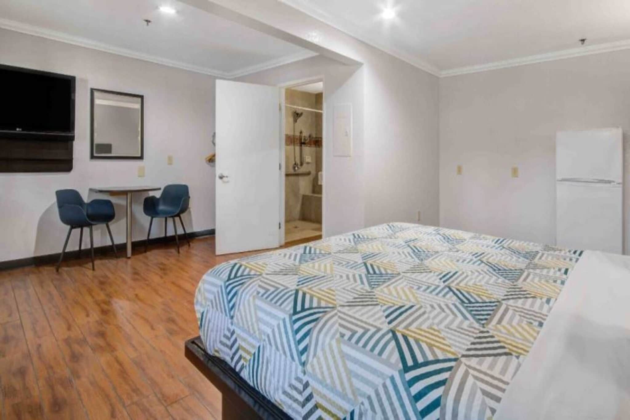 Une chambre à coucher avec une couvre-lit à motifs, un bureau avec des chaises, un miroir et un dressing.