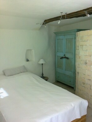 A bedroom with a bed, a nightstand, a lamp, and a wardrobe. - A charming room in the heart of a medieval village (Taulignan)
