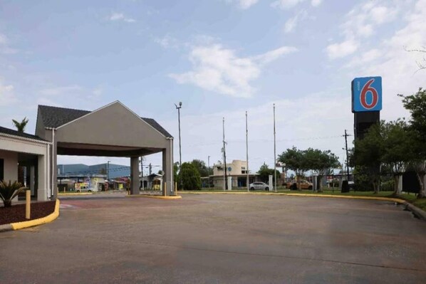 A parking lot with a covered area, a building with a '6' sign, and a clear sky. - 2 Queen Beds | Non-Smoking, Kitchen (Lake-Charles)