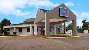 Um motel com um amplo estacionamento e entrada coberta.