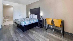 Een hotelkamer met een bed, nachtkastje en twee stoelen.