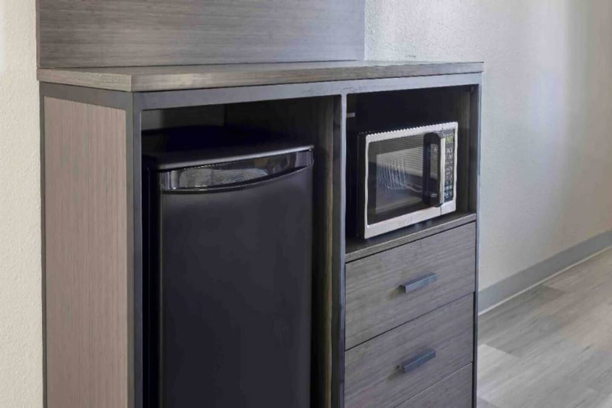 Una kitchenette compacta con microondas y un refrigerador pequeño.