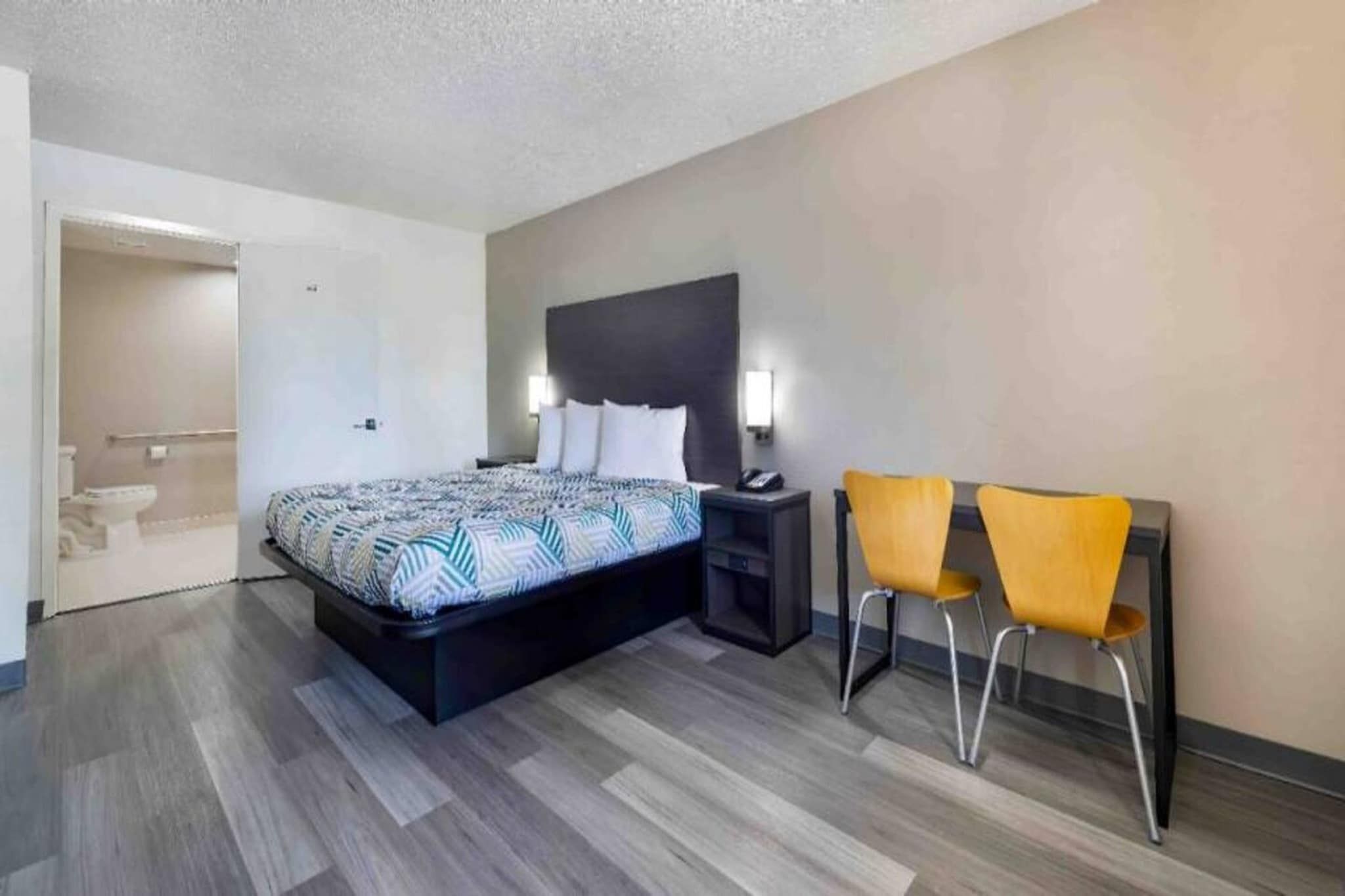 Une chambre d’hôtel comprenant un lit, une table de chevet, une commode et deux chaises.