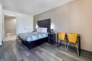 Ein Hotelzimmer mit Bett, Nachttisch, Beistelltisch und zwei Stühlen.