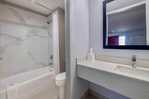 Ein Badezimmer mit einer Marmorbadewanne, einer Toilette und einem Waschbecken mit Spiegel darüber.