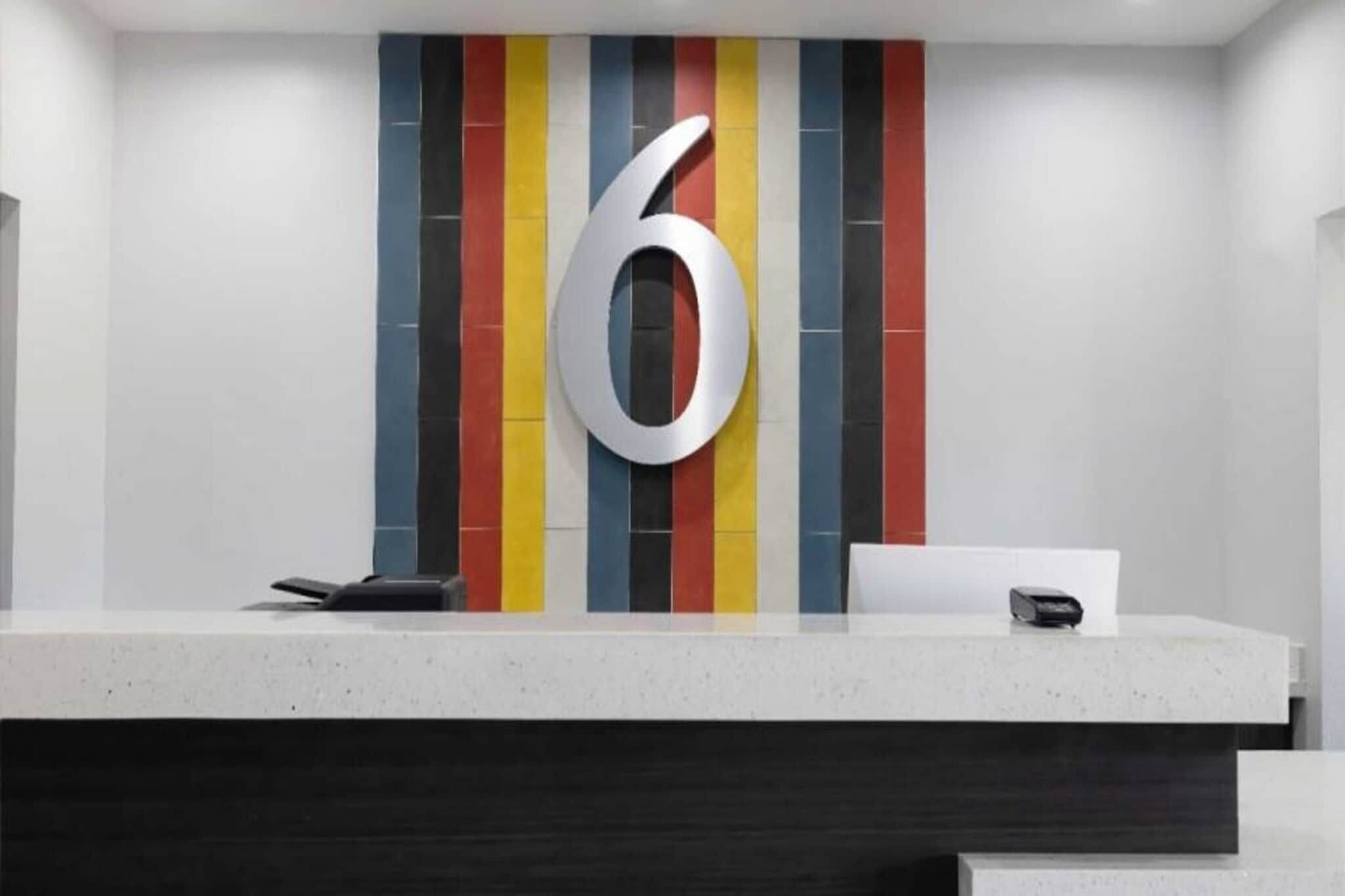 A reception desk with a large number '6' on the wall, a phone, and a small box, possibly a cash register.