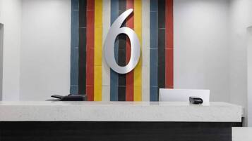 A reception desk with a large number '6' on the wall, a phone, and a small box, possibly a cash register.