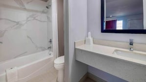 Um banheiro com banheira de mármore, vaso sanitário e pia com espelho acima.
