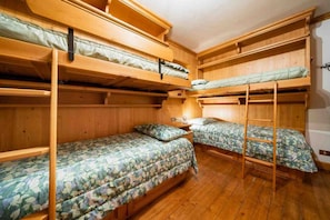 A room with bunk beds, wooden walls, and a wooden floor. - Spacious Apartment for 6 with Tofane Views and Panoramic Terrace (Cortina d'Ampezzo)