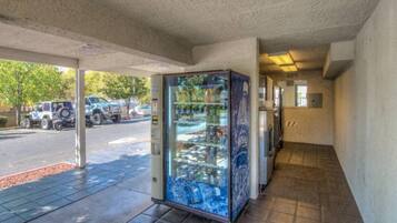 A vending machine with various items, a parking lot with vehicles, and a building entrance.
