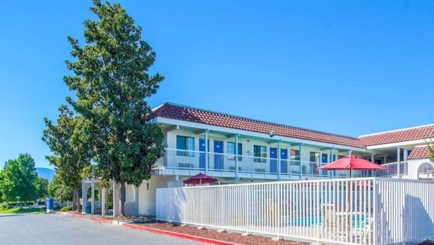 A motel with a fenced pool area, a covered patio, and a clear blue sky. - MS6 California|1Q|ADA|RI Shower (Redding CA)