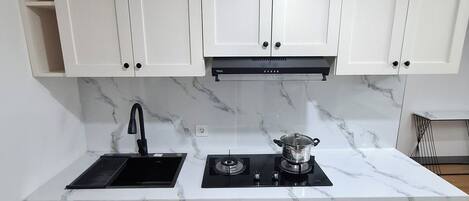 A kitchen with white cabinets, a black sink, a stove, and a built-in washing machine.