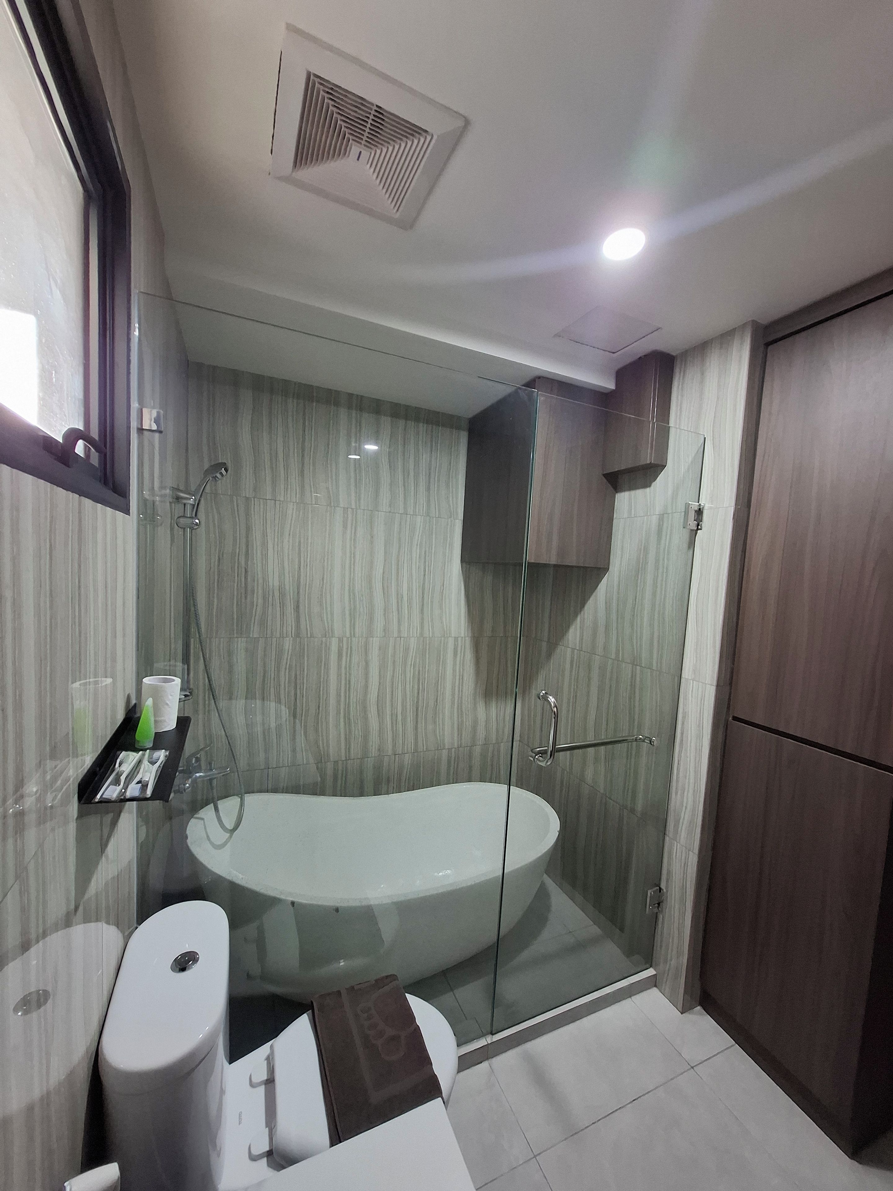 A modern bathroom with a glass-enclosed shower, a freestanding bathtub, and a toilet.