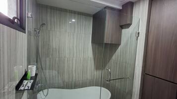 Un baño moderno con ducha de vidrio, una bañera independiente y un inodoro.