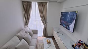 Una sala de estar moderna con sofá, una mesa de centro, un televisor de pantalla plana montado en la pared y un equipo de aire acondicionado.