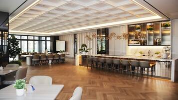 Un interior moderno con suelo de madera en espiga, una zona de bar con taburetes y un área de estar con mesas y sillas.