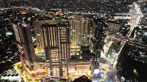 A high-rise building with multiple floors, surrounded by a well-lit urban area at night. - Apartement Pakuwon Bekasi by Monterra (Jawa Barat)