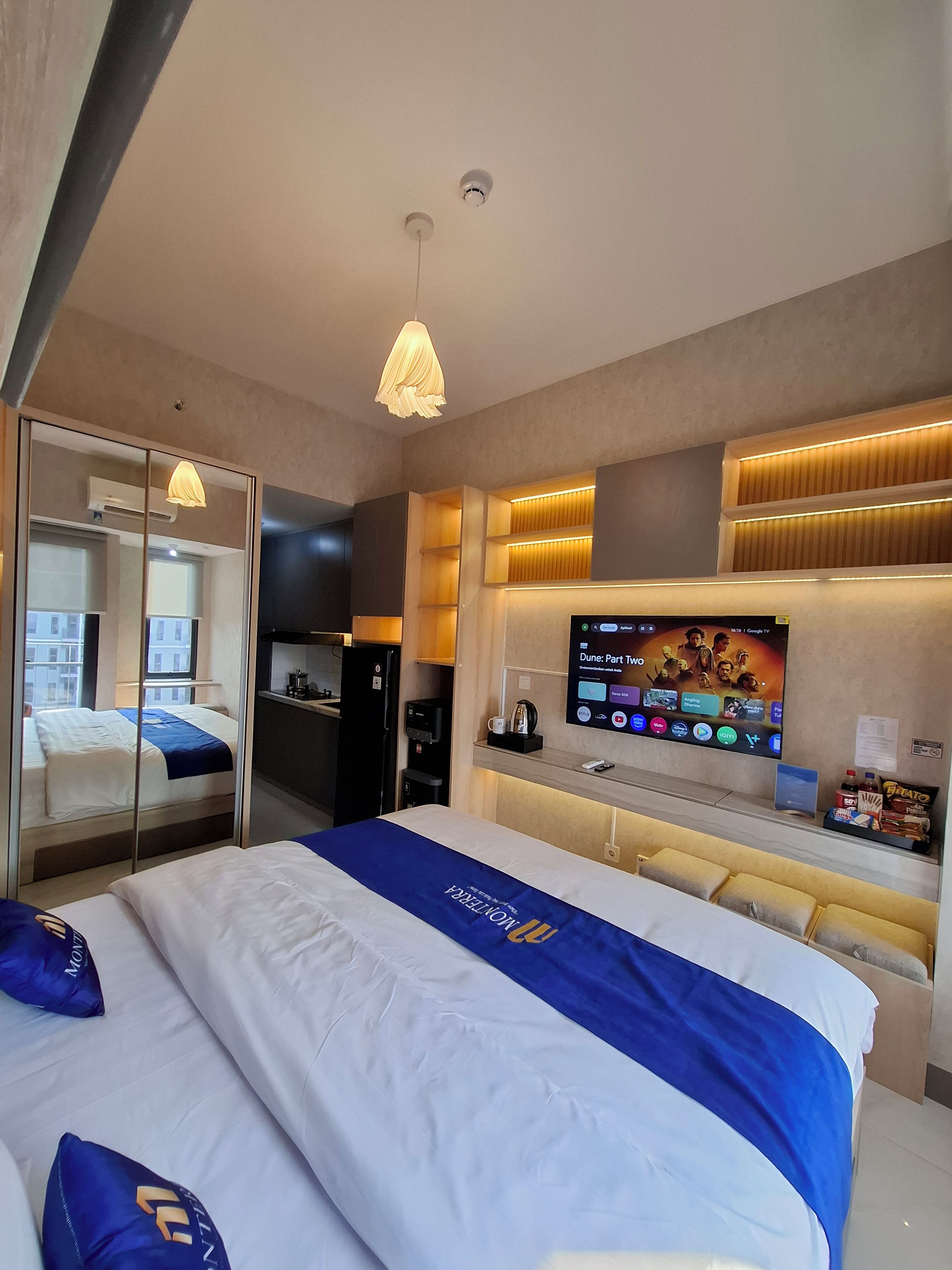 Ein Hotelzimmer mit Bett, Fernseher, Schreibtisch und Spiegel.