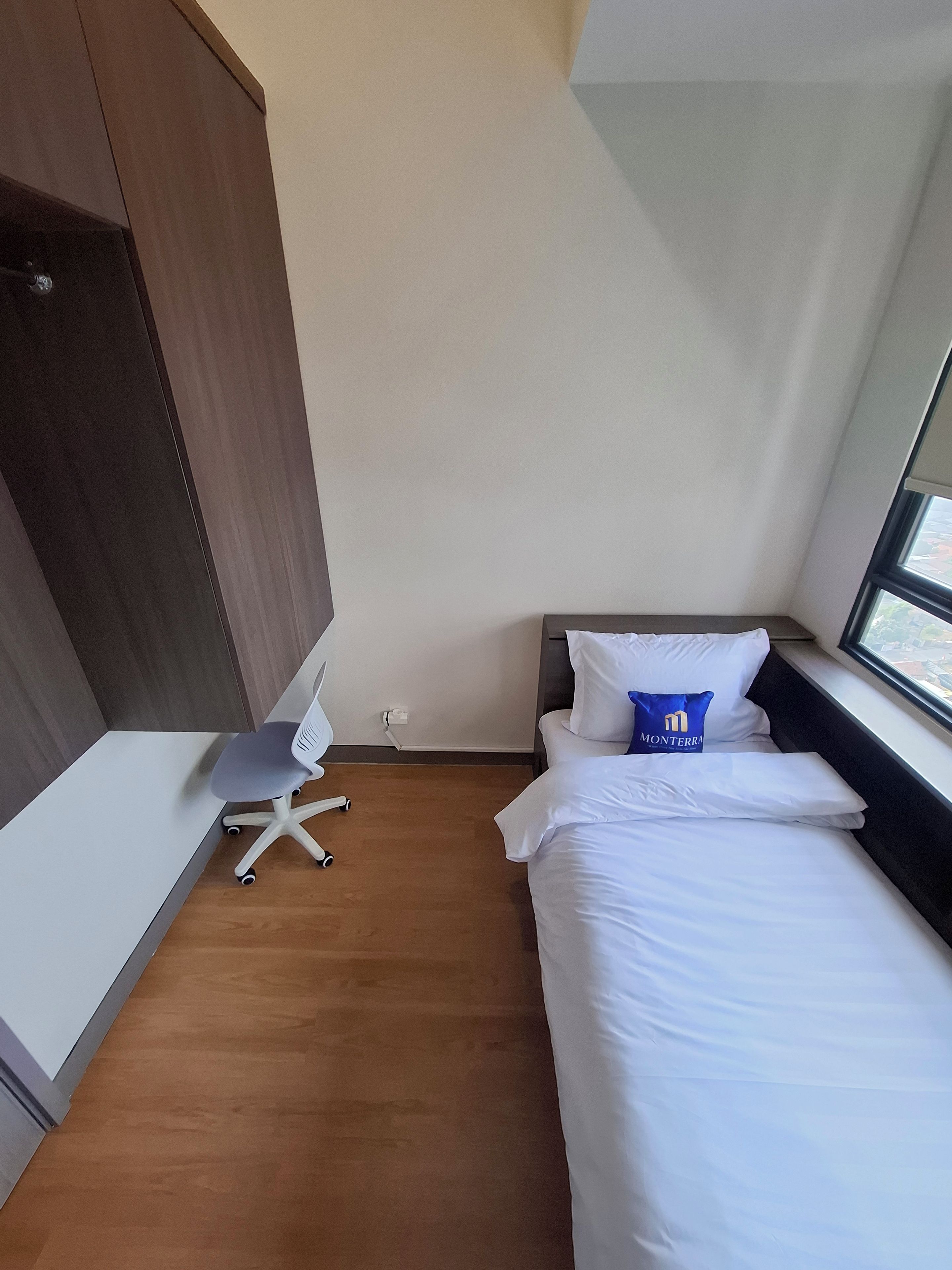 A hotel room with a bed, a desk with a chair, and a window.