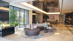 A modern lobby with a reception desk, seating area, and a large window. - Apartement Pakuwon Bekasi by Monterra (Jawa Barat)