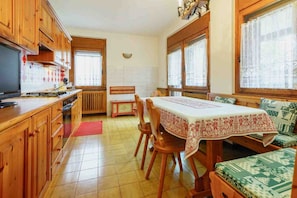 Una cucina con mobili in legno, un tavolo da pranzo con tovaglia e un divano con cuscini decorati.