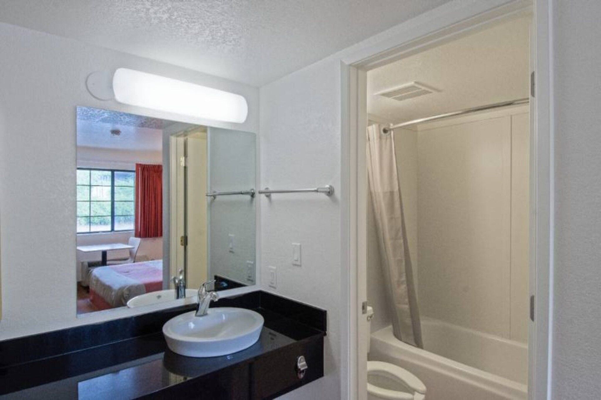 A bathroom with a sink, mirror, and shower.