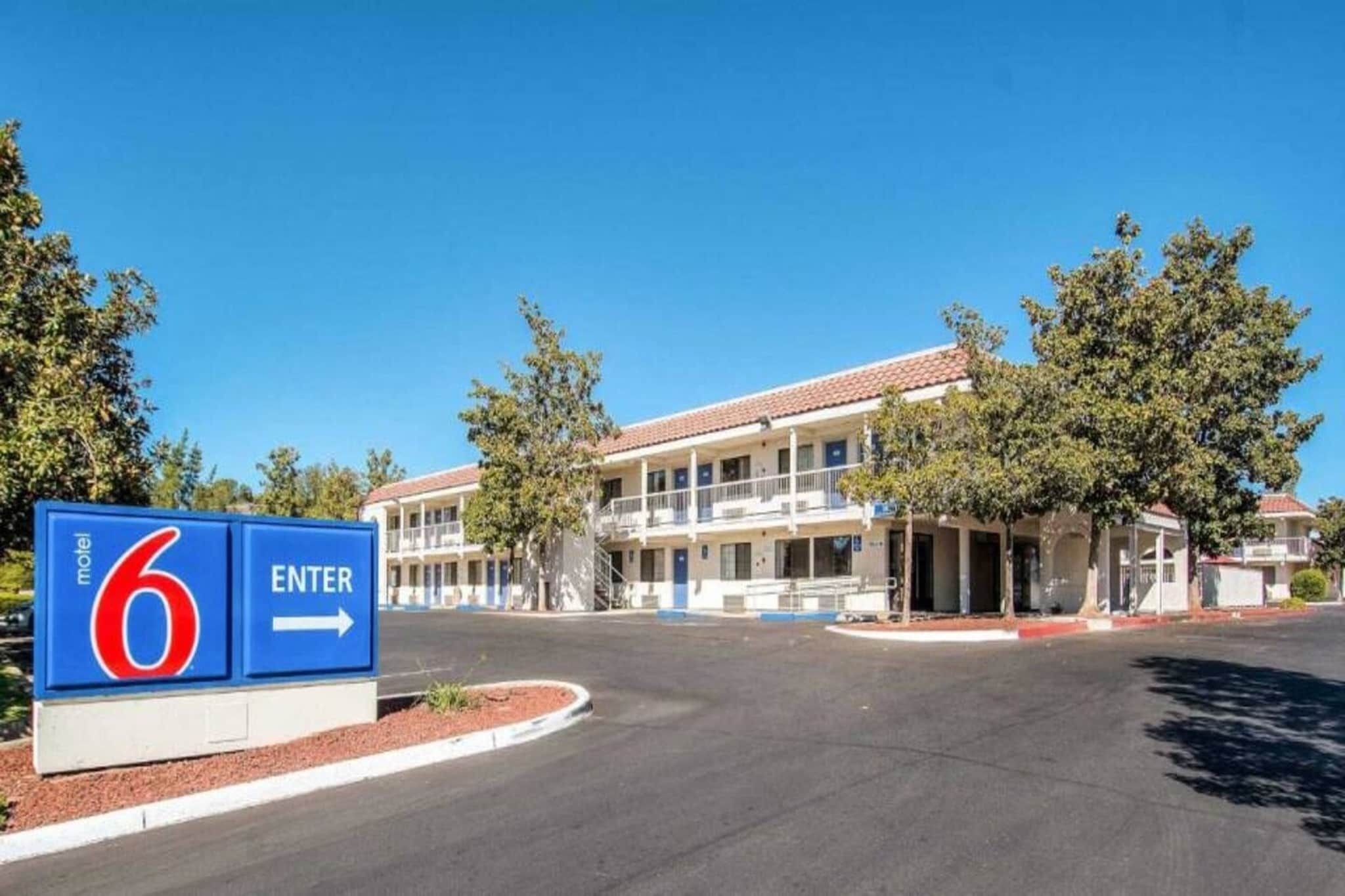 A motel with a clear entrance sign, a two-story building with a red-tiled roof, and a parking lot.