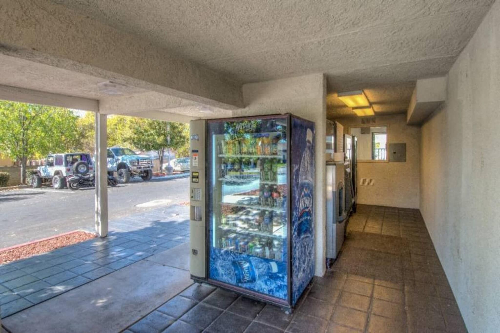 A vending machine with various items, a parking lot with vehicles, and a building entrance.