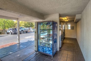 A vending machine with various items, a parking lot with vehicles, and a building entrance.