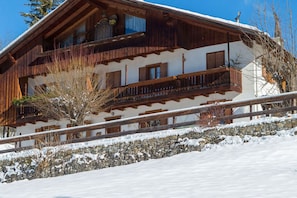 Una xalet de fusta amb fonaments de pedra, diversos balcons i un paisatge cobert de neu.