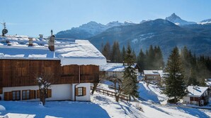 Ein verschneites Bergdorf mit Holzhäusern und freiem Blick auf die Berge.
