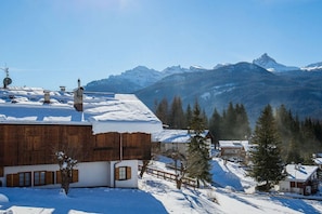 Un villaggio montano innevato con edifici in legno e una vista chiara delle montagne.