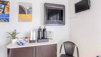 A reception area with a counter, a chair, a television, and some wall decorations.