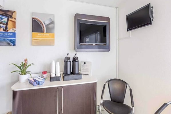 A reception area with a counter, a chair, a television, and some wall decorations.