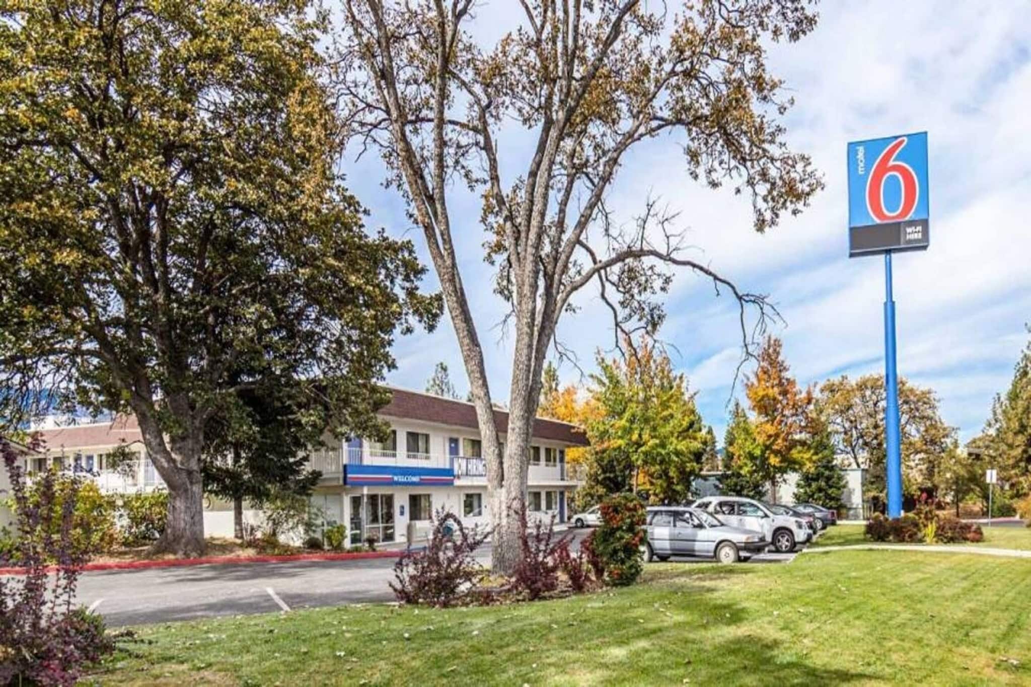 A motel with a '6' sign, a parking lot, and a building with a 'New Hire' sign.