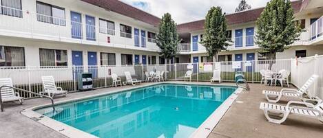 Et hotel med swimmingpool, udendørs siddepladser og et indhegnet område.