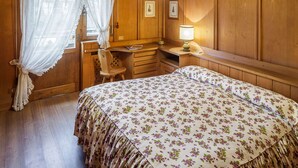 Ein Schlafzimmer mit einem Bett, einem Schreibtisch, einem Stuhl und einem Fenster mit Vorhängen.