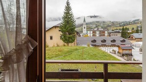 Blick aus einem Fenster auf eine Stadt mit einer Kirche, einem großen Baum und einer Rasenfläche.