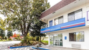 Un edificio con un letrero que dice 'WELCOME', un estacionamiento y un árbol en la parte delantera.