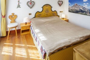 Una camera da letto con un letto in legno, un comodino con una lampada, uno sgabello di legno e una parete decorata con cuori.
