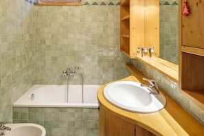 Un bagno con una vasca, un lavandino e un mobile bagno in legno.