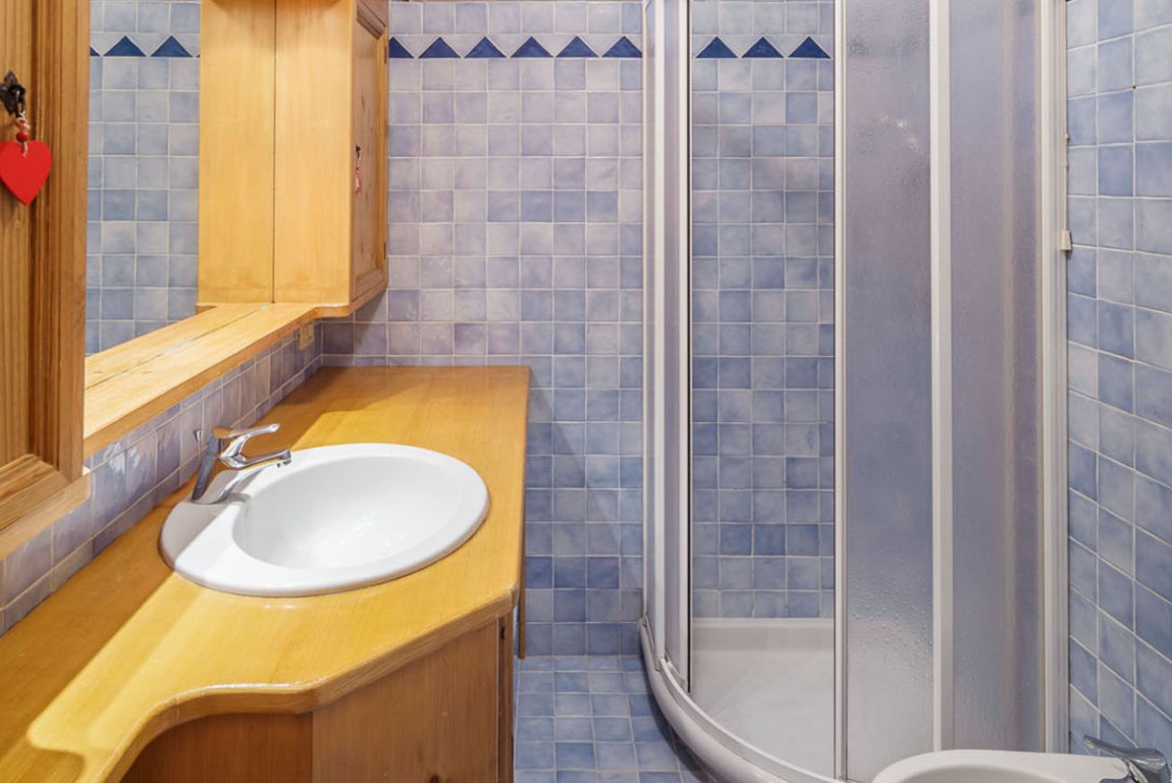 A bathroom with a wooden vanity, a white sink, and a glass shower enclosure.