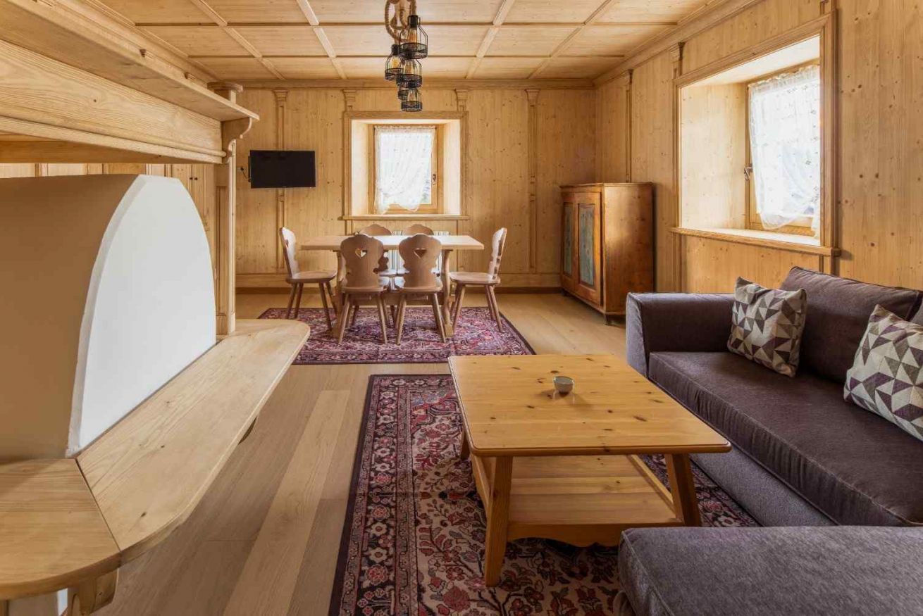 Un interior de madera con comedor, sofá y televisor.